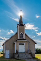 Fototapeta na wymiar Suburst over the steeple of the historic Nordland Lutheran Church on the prairies near Stewart Valley, Saskatchewan, Canada
