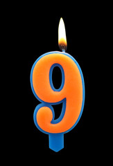 Burning birthday candle isolated on black background, number 9