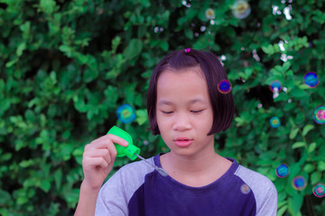 A little girl blowing soap bubbles. child happy play in park