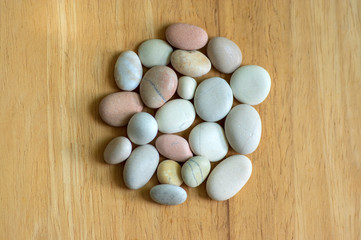 Obraz premium Group of white, grey and light brown stones on wooden background, pebbles beach, circle mandala shape
