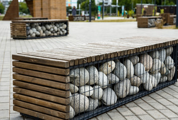 Street landscape. Recreation area. Original benches in the form of wooden boxes filled with boulders. Selective focus.
