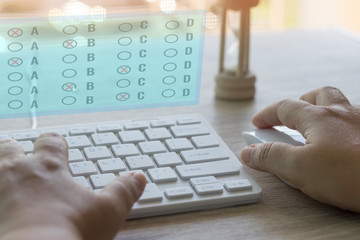 Dry hand of adult student using white keyboard on table to do test examination with multiple choice...