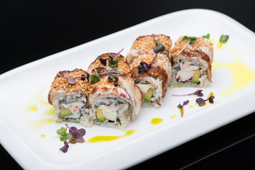 sushi in a plate on a black background, close-up. fish roll