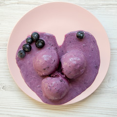 Blueberry ice cream balls on a pink plate, overhead view. From above, top view.