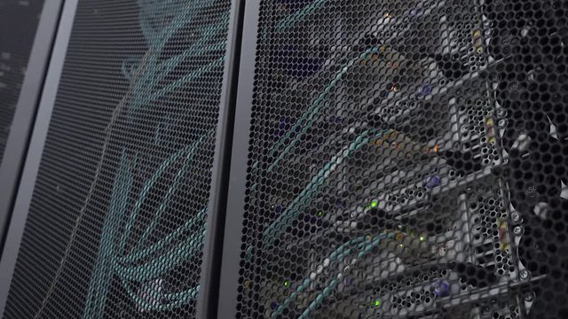 Server rack flashing led lights are in a modern data center are located behind an iron door with round openings.
