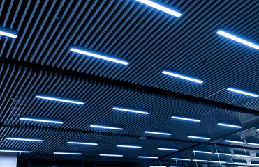 Leading lines and low light view. Fluorescent lamps open in row on the ceiling beautiful and modern inside the building.
