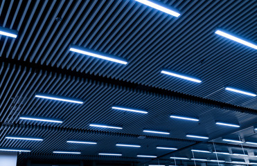 Leading lines and low light view. Fluorescent lamps open in row on the ceiling beautiful and modern...
