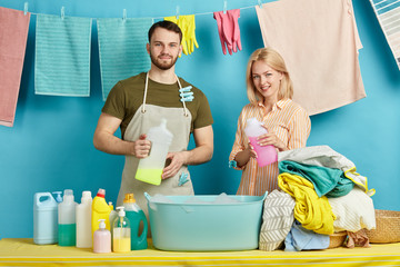 beautiful blonde housewife and her husband testing new washing liquid, soap wjile working in the laundry room. close up portrait. hanging clean clothes hanging on the clothesline