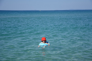 Little boy with inflatable ring swimming in the sea. Child with a floating ring enjoy in water