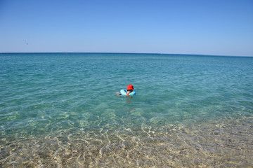 Little boy with inflatable ring swimming in the sea. Child with a floating ring enjoy in water