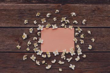 Blank card with white flowers on vintage wooden table. Flat lay, copy space.
