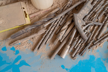 Wood drill bits and steel tools on a table covered with wood dust and chips. Concept of abandonment and mess