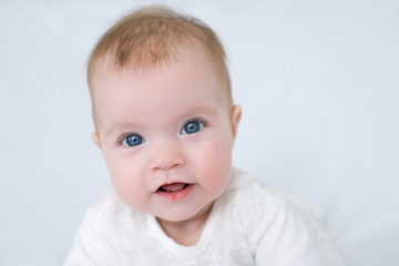 large portrait of little girl with blue eyes in white dress on white background, little girl looking at camera