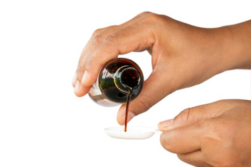 medical syrup flowing from a bottle into a spoon in the hands