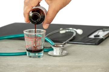 medical syrup flowing from a bottle into a spoon in the hands