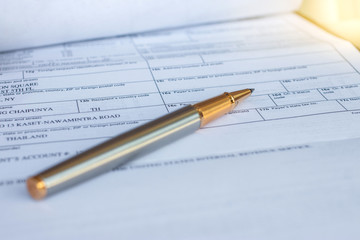Low angle view of golden pen lying on white sheet of paper in a folder with another set of paperwork