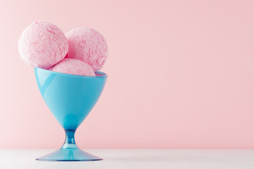 Refreshing classic pink creamy ice cream balls in elegant blue bowl on white wooden table and soft light pastel pink background.