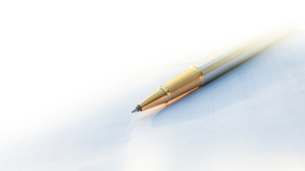 Low angle view of golden pen lying on white sheet of paper in a folder with another set of paperwork