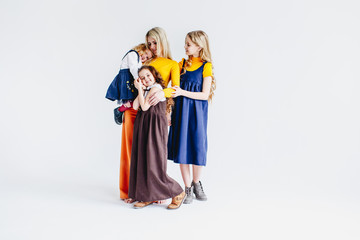 Fototapeta premium A mother with three cute daughters playing with wooden toy train. A family of four girls. Girls hugging their mother