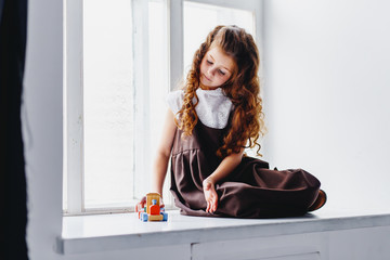 A girl playing with a toy train on the windowsill