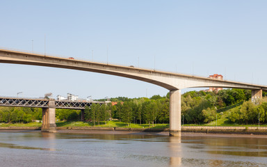 Traffic is seen crossing Redheugh Bridge over the River Tyne and in the background is the King Edward VII railway bridge.  The bridges connect Newcastle upon Tyne and Gateshead.
