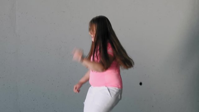 Girl teenager dancing on a gray background. Street dance