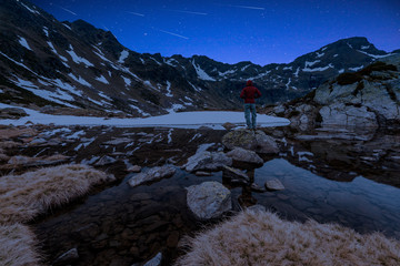 Man Watching Perseid MEteor Shower at Starry Night in High Mountains
