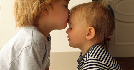 Babygirl and babyboy kissing on the beach in straw hats