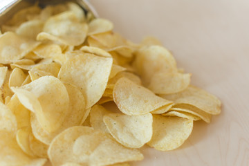 Heap of potato crisps on wooden background. Potato chips, unhealthy eatting.