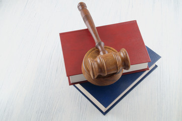 Judge's gavel and blue and red legal books on wooden table