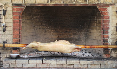 The carcass of a sheep is cooked on a spit over an open fire