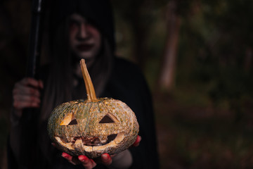 Woman ghost horror her have scythe and pumpkin on hand in forest,