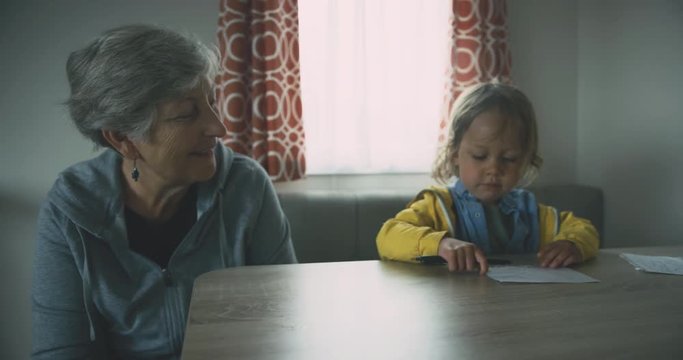 Little toddler drawing with his grandmother at a table
