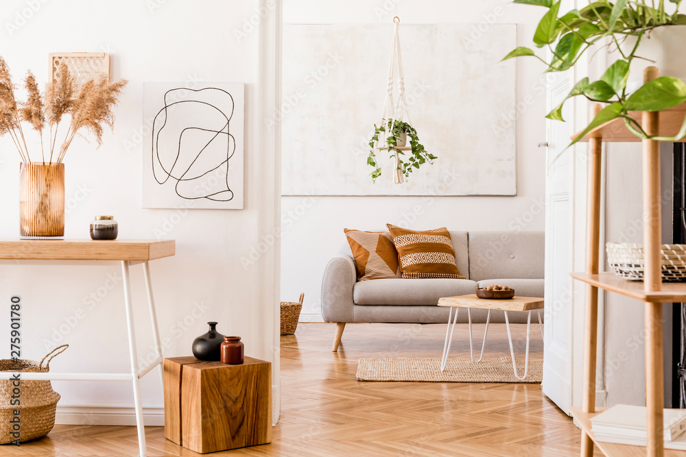 Wall mural The stylish boho interior of living room at nice apartment with gray sofa, wooden desk, bamboo shelf, coffee table,  honey yellow pillows, plants and elegant accessories. Mock up paintings on the wall