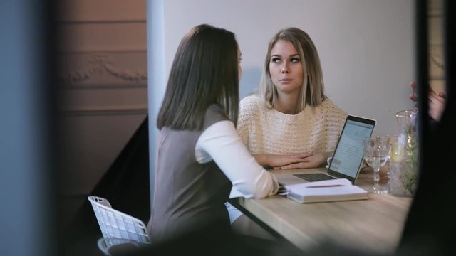The dialogue between friends in a cafe seated at a table near the window. Cheerful girls and a man discuss work and rest during worktime lunch.