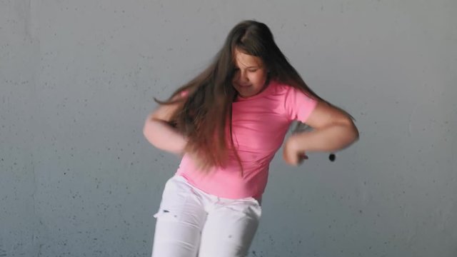 Girl teenager dancing on a gray background. Street dance