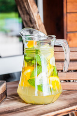 A jug of homemade refreshing icy citrus lemonade on the terrace on a hot summer day. Concept of...
