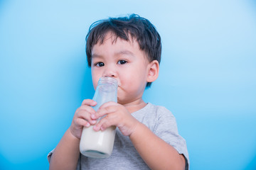 Asian little child boy about 2 year drinking milk from bottle glass itself