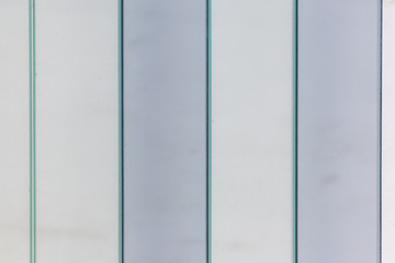 Verschiedenfarbige Glasscheiben einer Fassade mit senkrechten Linien und klaren Formen zeigt ein schönes Muster als Glashintergrund mit klaren Linien, milchigem Glas als undurchsichtigem Sichtschutz