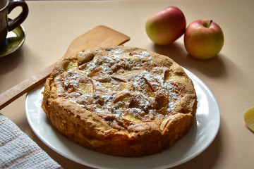 Apple pie on a white plate, coated in sugar powder.
