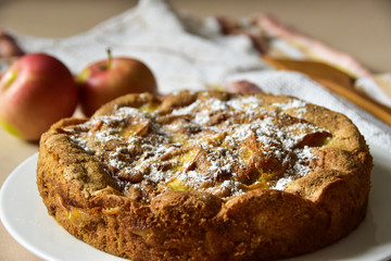 Apple pie on a white plate, coated in sugar powder.