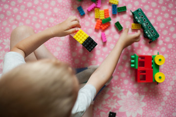 Small hands of the child collects the bright plastic colored Designer. Educational toys and Early learning