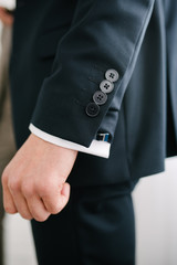 Man in suit with hand adjusts sleeve of shirt close-up