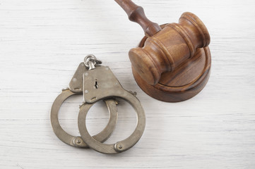 Judge gavel and handcuffs on white table, court concept