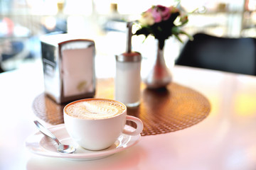 cup of coffee on a table in a cafe morning sunlight blur