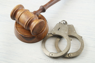 Judge gavel and handcuffs on white table, court concept