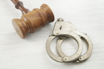 Judge gavel and handcuffs on white table, court concept