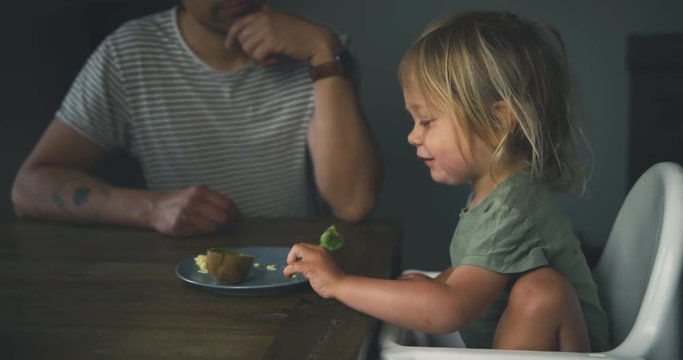 Little toddler having breakfast with is parents at the table