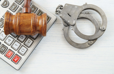 Judge gavel, calculator and handcuffs on white table. Financial fraud concept