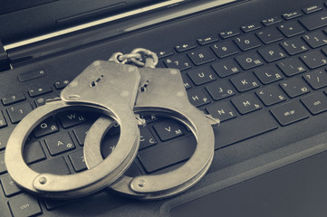 Cyber crime concept, handcuffs on laptop keyboard